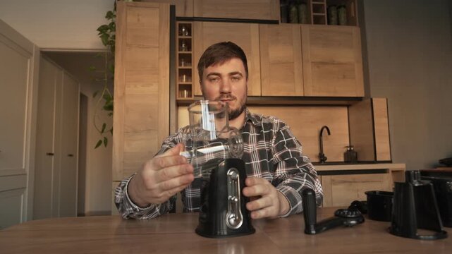 A male householder in the kitchen is assembling a manual vegetable slicer.