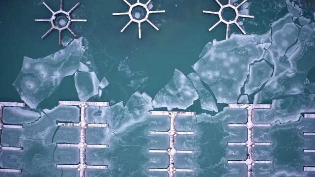 Dramatic drone shot of frozen harbor waters and winter ice on Lake Michigan near Chicago Loop skyscrapers.