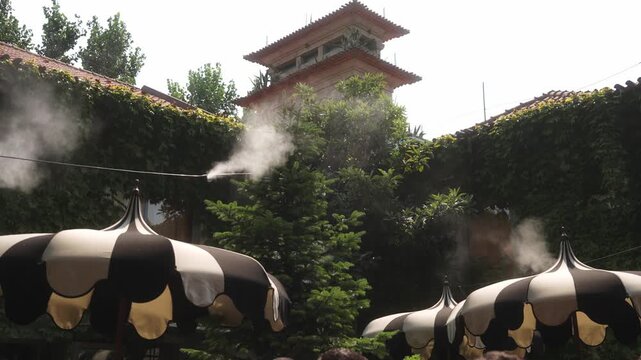 Striped umbrellas with water mist sprayers in outdoor courtyard