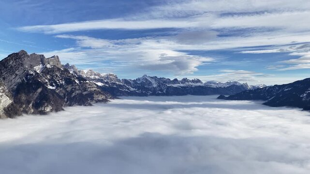 Walensee region Swiss alps above cloud inversion near Amden, Walenstadt, Quinten and Mols, Switzerland, snowy alpine peaks and fog valley under blue sky.