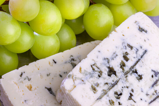Blue cheese with yellow grapes close-up