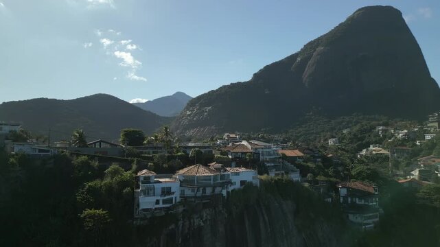 Joatinga Beach and neighborhood, Brazil. Shot features high-end coastal housing and hills in 4K Apple ProRes 422. Ascending right panning aerial.