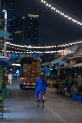 Obraz premium Night market street with cyclist riding under string lights