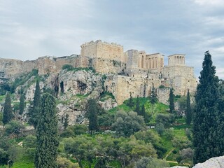 Obraz premium Low-angle view of the Acropolis of Athens with ancient ruins glowing in sunlight against a clear blue sky
