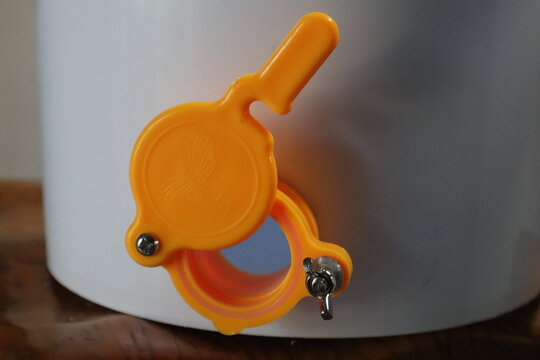 Close up of a honey gate also known as a honey tap or honey valve on a white bucket