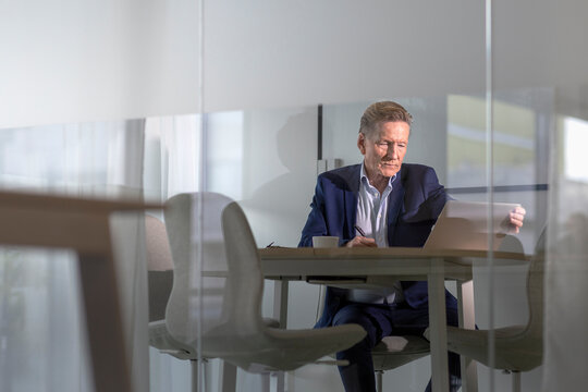 Senior male entrepreneur working on laptop while sitting at office
