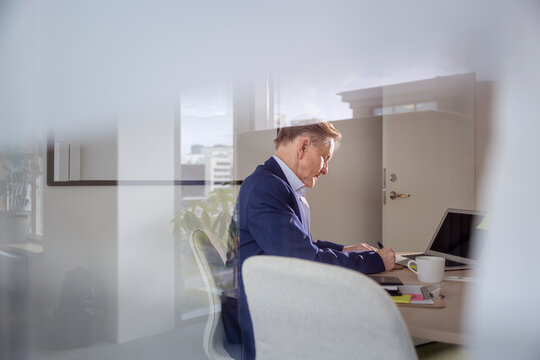 Side view of senior businessman working in office meeting room