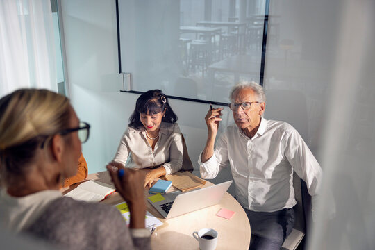 Senior manager sharing ideas with colleagues in team meeting at office