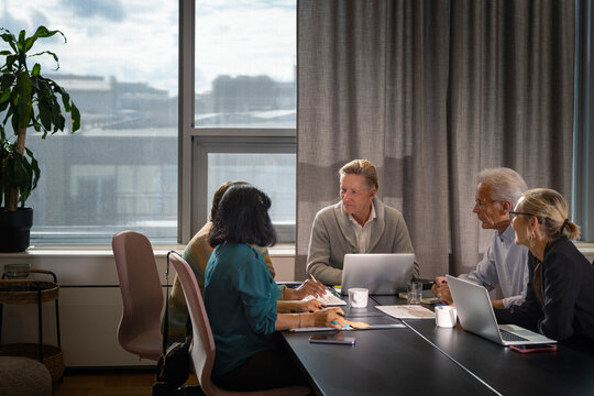 Team of senior corporate professionals sitting around table during office team meeting