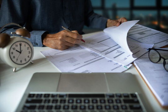 close up shot, asian businessman working late on desk with laptop and documents and receive compensation for overtime work