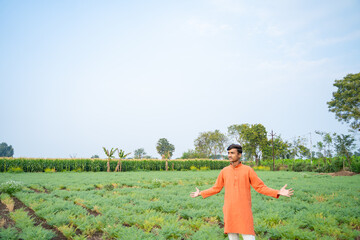 Fototapeta premium young indian farmer standing at green agricultural field