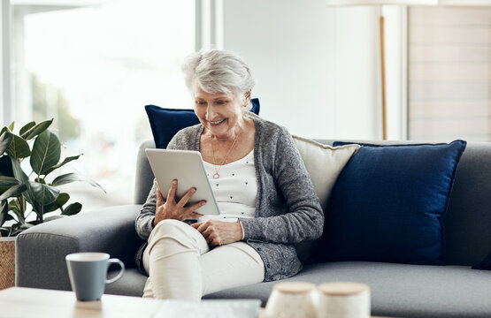 Old woman, tablet and relax on sofa in home for streaming, video and notification on web in lounge. Elderly person, smile and tech with application, film or movie subscription on couch in retirement