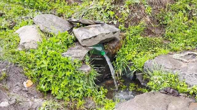 4K Landscape shot of water stream being directed by a small plastic water bottle as seen during the trek to Para Lam waterfall in Pangi Valley, Chamba district, Himachal Pradesh, India. Natural view.