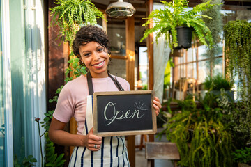 Naklejka premium Smiling florist holding 'Open' sign