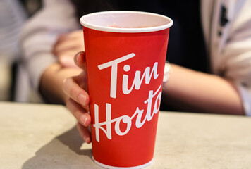 Naklejka premium Toronto, Canada - September 15, 2025: Hand holding a hot drink from Tim Hortons.