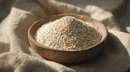 A generous pile of tiny, delicate white quinoa grains overflowing from a rustic wooden bowl