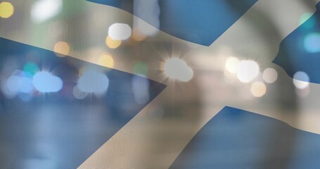 Fototapeta premium Displaying Saltire flag showing woven texture at night, with bokeh lights and lens flares
