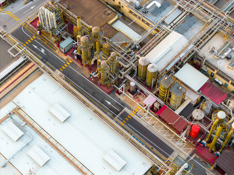 Aerial view of industrial buildings and structures create a tapestry of geometric shapes and contrasting textures under the soft sunlight, Settecamini, Lazio, Italy.