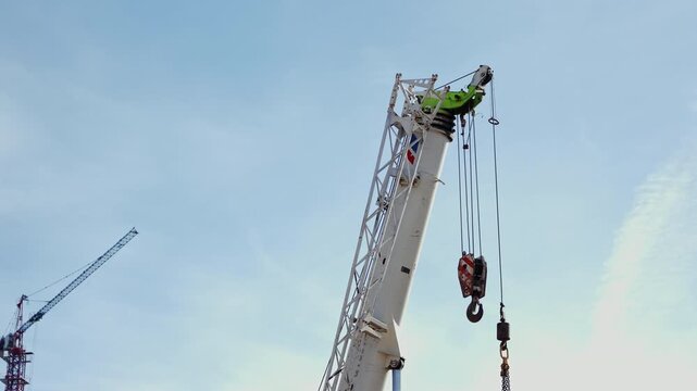 Telescopic crane boom with hook and cables against sky