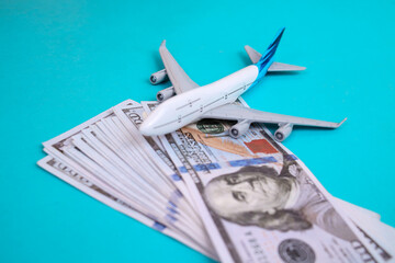 Airplane model on stack of US dollar bills for travel expenses