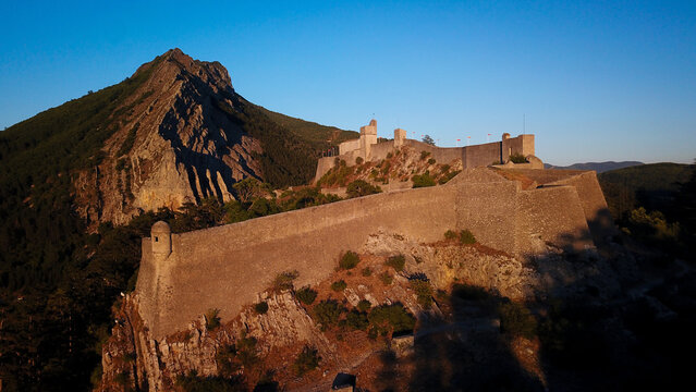 Aerial view of the imposing Citadel of Sisteron perched atop a rocky crag, its ancient stone walls glowing in the soft light of dawn, Sisteron, Provence-Alpes-Cote d'Azur, France.