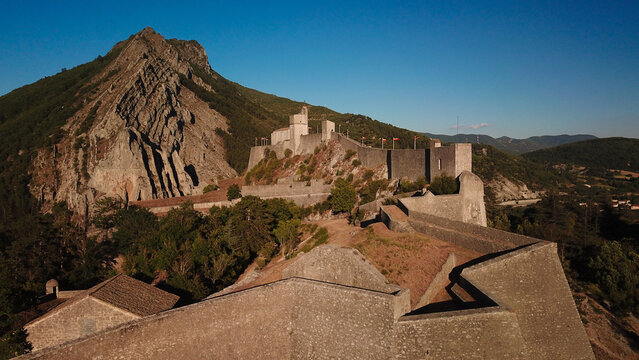 Aerial view of the imposing Citadelle de Sisteron fortress clinging to the rugged mountain, a stark contrast against the azure sky, Sisteron, Provence-Alpes-Cote d'Azur, France.