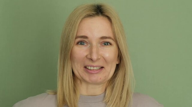 Blonde caucasian woman on a green background expressing a range of negative emotions. From initial surprise and shock to disgust. Disappointment. And then playfully rejecting something with her hands