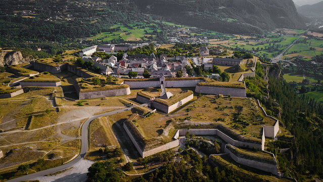 Aerial view of the fortress town exhibiting intricate Vauban fortifications against a lush, mountainous backdrop, Mont-Dauphin, Provence-Alpes-Cote d'Azur, France.