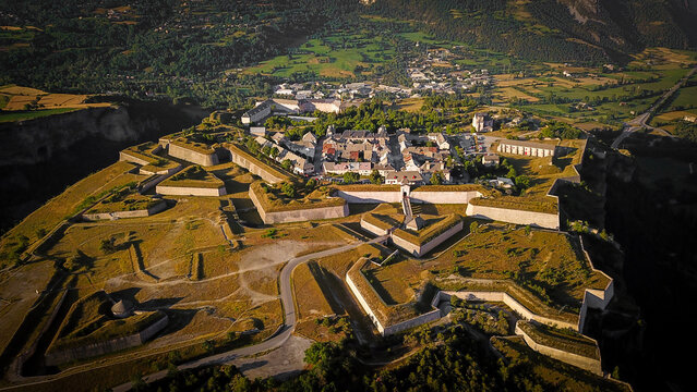 Aerial view of the star-shaped fortress, a testament to Vauban's military genius, stands proudly against the backdrop of the surrounding mountains, Mont-Dauphin, Provence-Alpes-Cote d'Azur, France.