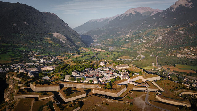 Aerial view of the star-shaped fortress with its robust ramparts and historic buildings nestled amid lush greenery and majestic mountains, Mont-Dauphin, Provence-Alpes-Cote d'Azur, France.