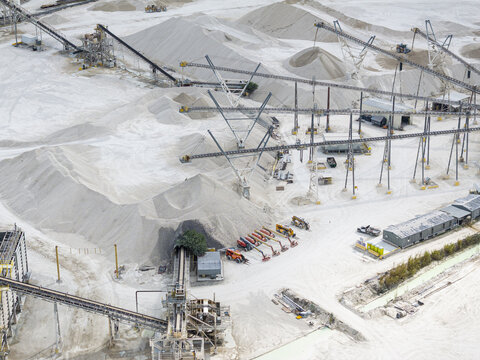 Aerial view of a sprawling limestone quarry where stark white mounds contrast with the industrial machinery, creating a surreal landscape, Miami, Florida, United States.