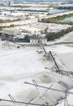 Aerial view of the stark white limestone quarry contrasting against the distant city skyline and blue waters, Miami, Florida, United States.