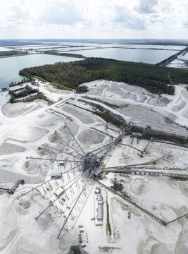 Aerial view of a stark, geometric quarry where brilliant white stone contrasts sharply with the deep blue water and verdant trees, Miami, Florida, United States.