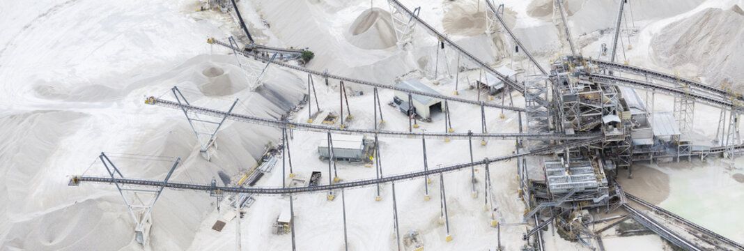 Aerial view of a monochrome landscape where conveyor belts snake through white sand dunes in a limestone quarry, Miami, Florida, United States.