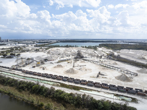 Aerial view of an industrial landscape where stark white quarry contrasts with the deep blue waters and vibrant green vegetation, Miami, Florida, United States.