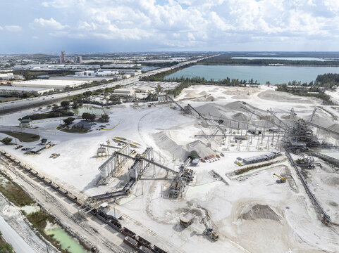 Aerial view of a stark white quarry juxtaposed against the blue water and sky, a scene of industry and nature's beauty coexisting, Miami, Florida, United States.