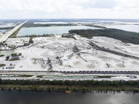 Aerial view of a vast limestone quarry where the stark white of the extracted rock contrasts with the dark waters and verdant borders, Miami, Florida, United States.