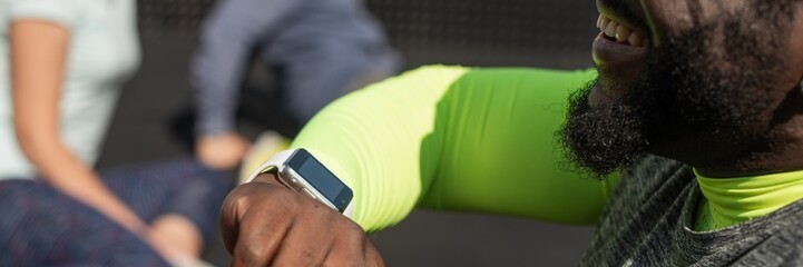Man checking smartwatch during outdoor workout. Focus on smartwatch. Fitness and technology. Group...
