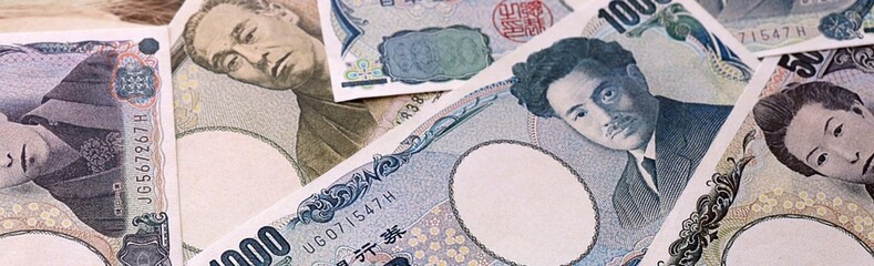 Japanese yen money bills pile on table. Japan banknotes of JPY currency close up. © Larysa