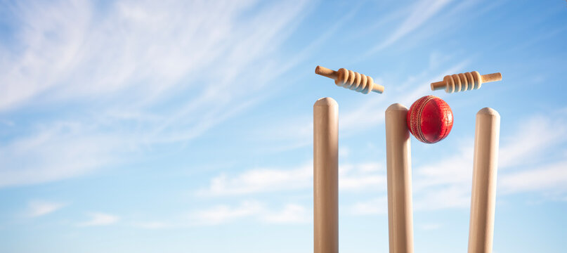 Cricket ball hitting wicket stumps and bails bowled out background