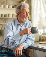 Senior man contemplating morning with coffee cup in kitchen