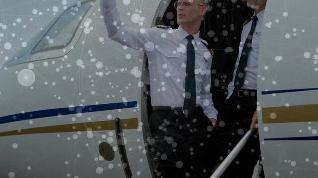 Speckles thinning, airline crew stepping onto stairs one signaling ramp other holding rail watching