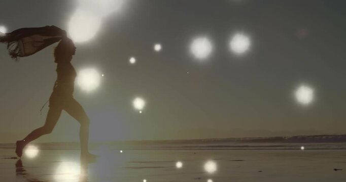 Bokeh rising cueing woman entering left bounding lifting scarf on wet sand mirroring sun for travel