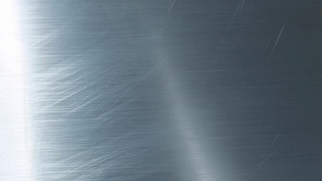 Close-up of brushed metal surface showcasing texture and reflections. Ideal for industrial design, modern aesthetics, and product backgrounds