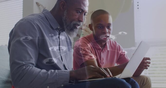 Dad following son pointing, typing on laptop while network tech graphics gradually enabling sharing