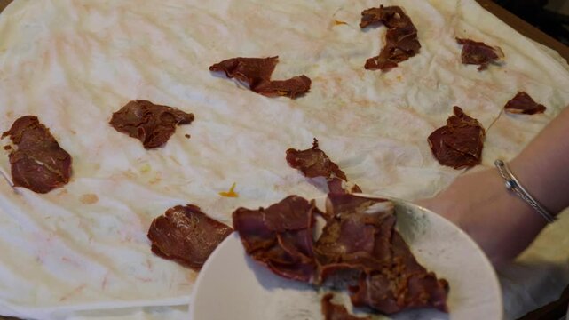 Placing Turkish Pastirma Slices on Dough for Homemade Borek