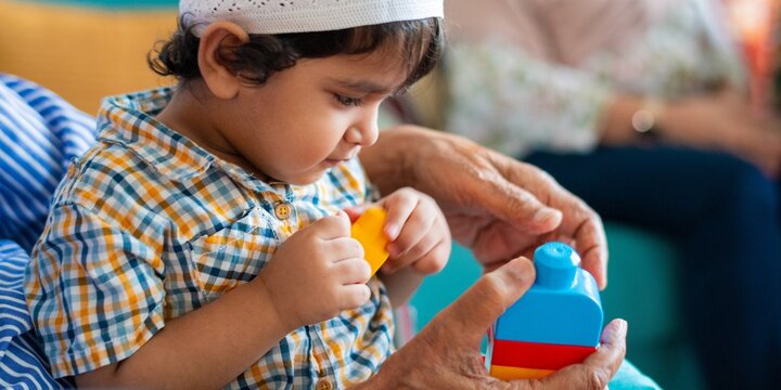 Child playing with colorful blocks, guided by an adult's hands. Focus on learning and play. Close-up of child and blocks, emphasizing interaction and play. Young boy child photo with toys.