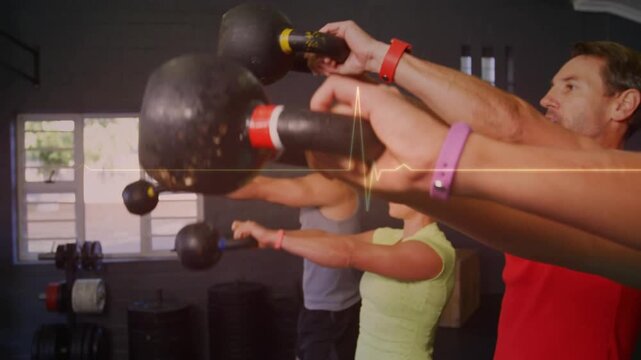 Swinging group of four adults wearing tank tops and wristbands, performing kettlebell swings in gym