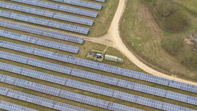 Aerial view of gleaming solar panels stretch across the landscape near the former RAF Alconbury, a stark contrast against the golden fields, Huntingdon, Cambridgeshire, United Kingdom.