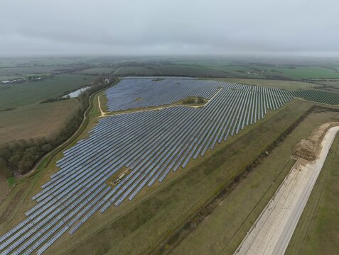 Aerial view of solar panels gleaming under a muted sky near the former RAF Alconbury, a testament to renewable energy, Huntingdon, Cambridgeshire, United Kingdom.